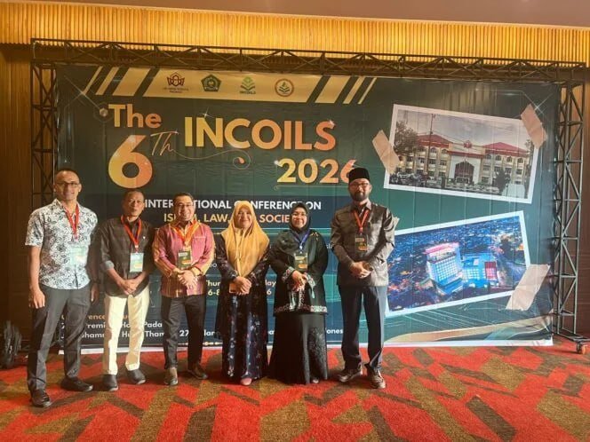 A group of esteemed professors and scholars, predominantly male with a few females, gathered in a modern conference hall, attentively listening to a speaker at a podium. The atmosphere is intellectual and collaborative. Banners or screens in the background subtly display event logos like 'FORDIPAS' and 'INCOILS'. One prominent figure, a distinguished Indonesian man in his 50s or 60s, possibly Prof Syamsul Rijal, is seen in a formal setting, perhaps receiving an acknowledgment or engaging in discussion. The setting conveys a sense of academic leadership and scholarly exchange at an international conference. A group of esteemed professors and scholars, predominantly male with a few females, gathered in a modern conference hall, attentively listening to a speaker at a podium. The atmosphere is intellectual and collaborative. Banners or screens in the background subtly display event logos like 'FORDIPAS' and 'INCOILS'. One prominent figure, a distinguished Indonesian man in his 50s or 60s, possibly Prof Syamsul Rijal, is seen in a formal setting, perhaps receiving an acknowledgment or engaging in discussion. The setting conveys a sense of academic leadership and scholarly exchange at an international conference.